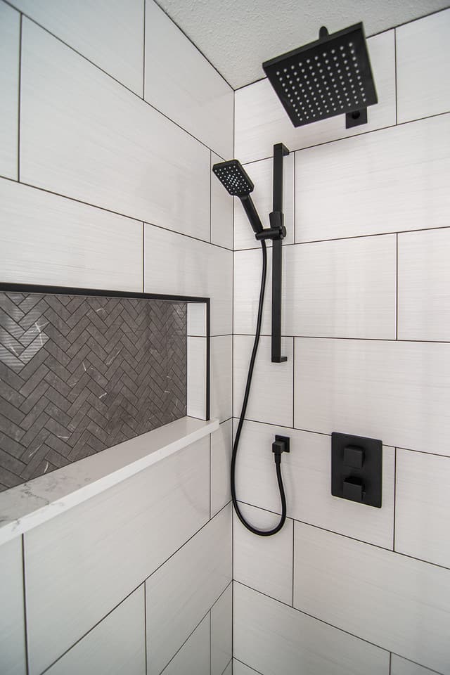 accent tile grey herringbone shower niche with black accents and dark grout