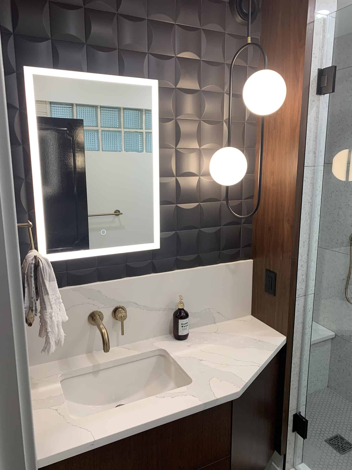 masculine bathroom renovation with modern fixtures and black square 3d tile